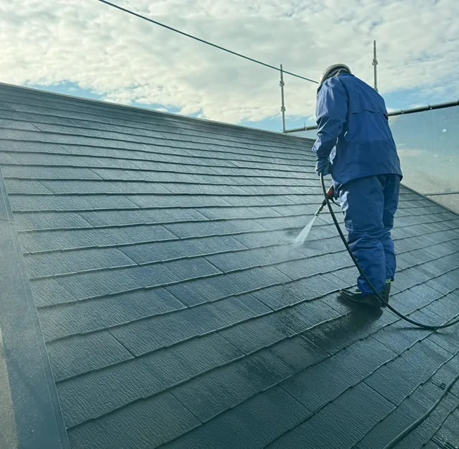 職人さんが高圧洗浄機で屋根を丁寧に清掃する様子。