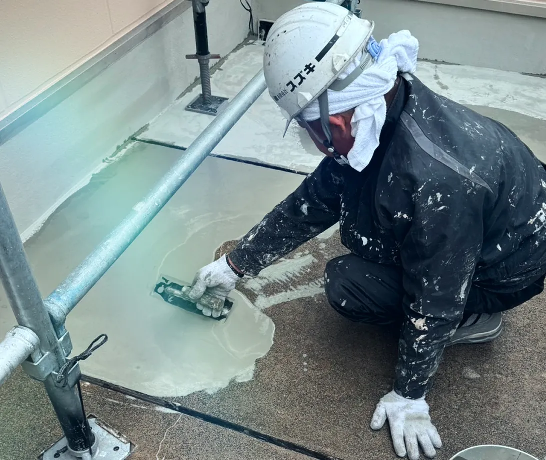 グレーのコンクリートに、白いモルタルが丁寧に塗布される。